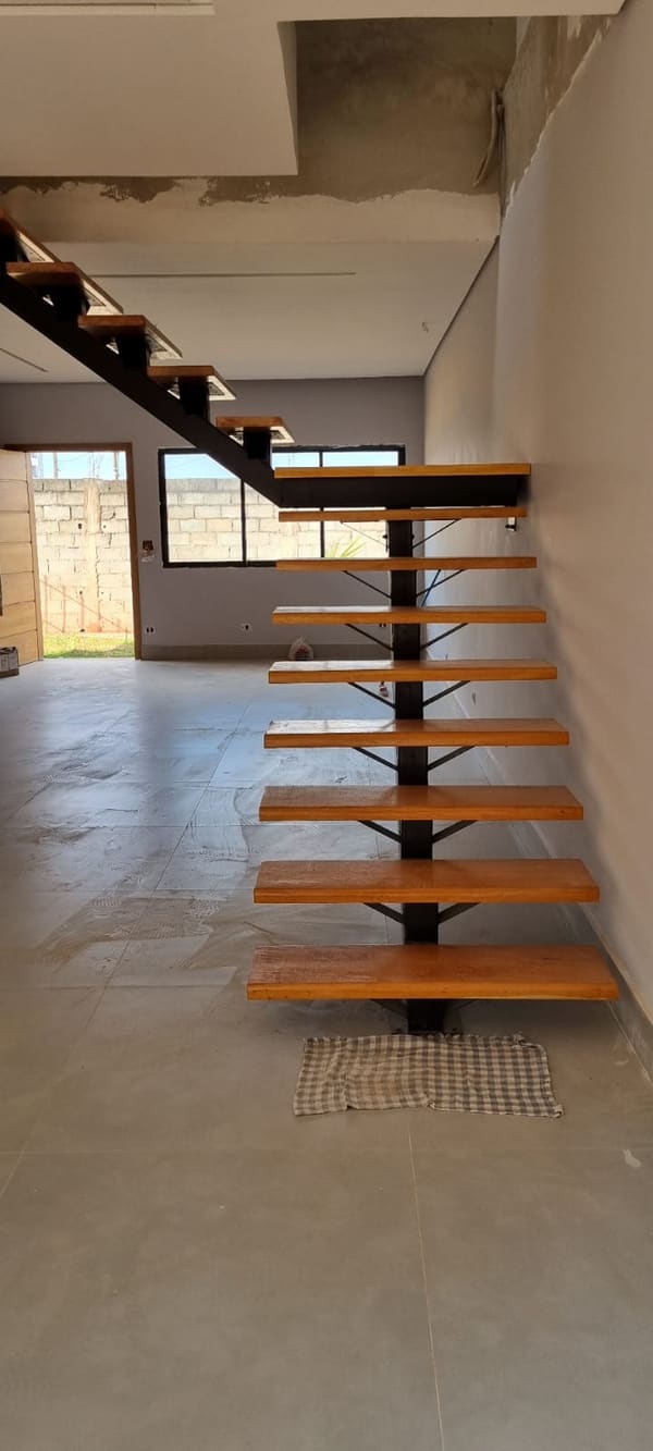 Escada com estrutura metálica central e degraus de madeira em ambiente interno