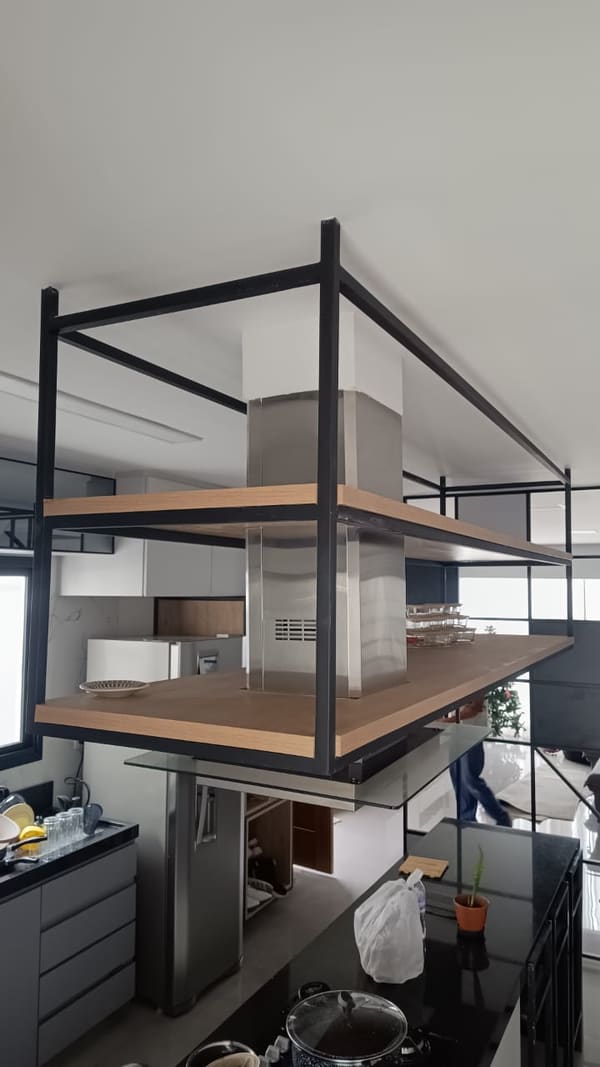 Estrutura metálica preta suspensa no teto sobre a bancada da cozinha, com prateleiras de madeira