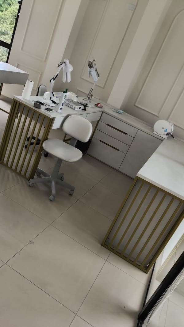 Bancadas com bases metálicas douradas de barras verticais em sala de atendimento